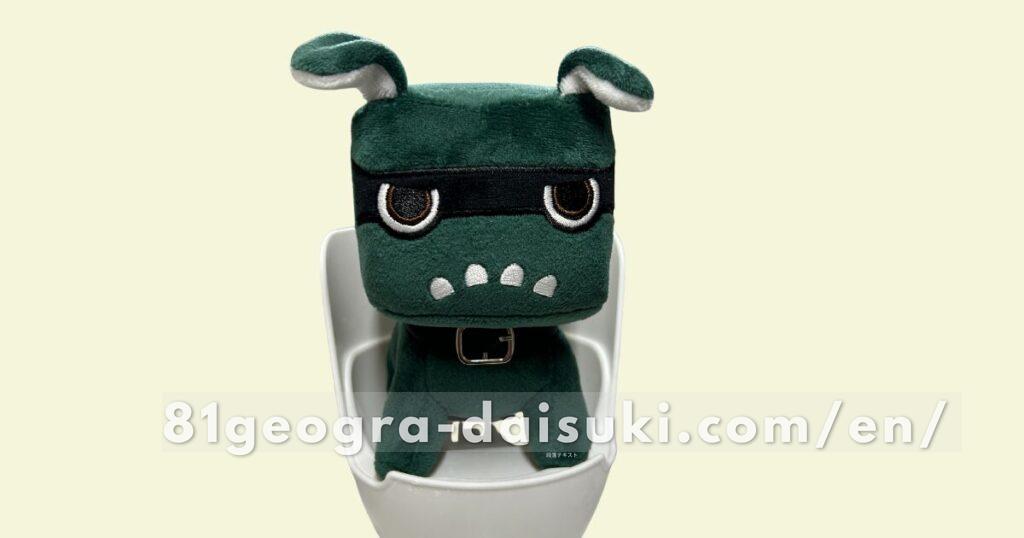 Delimaru plushie sitting upright on a white smartphone holder from Daiso.