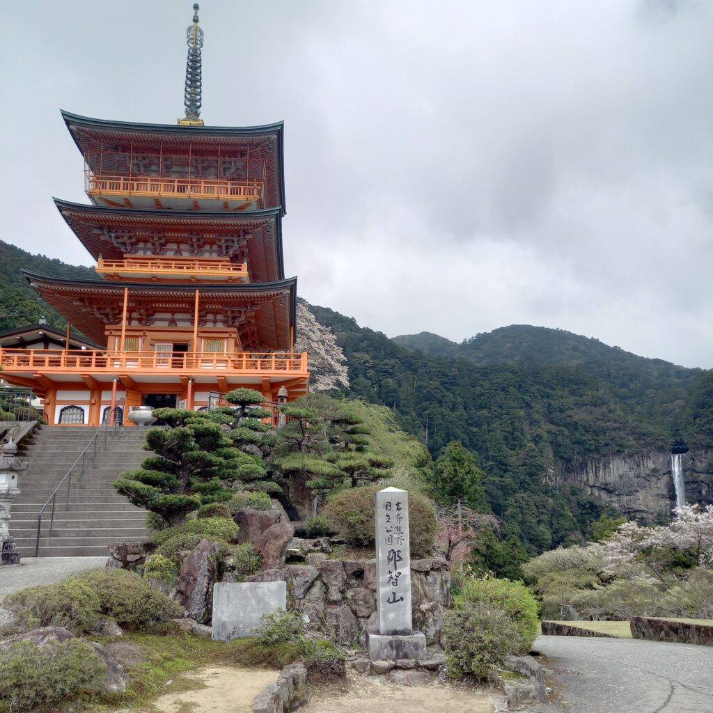 Nachi-san three-story pagoda and Nachi Falls in the distance, with cherry blossoms