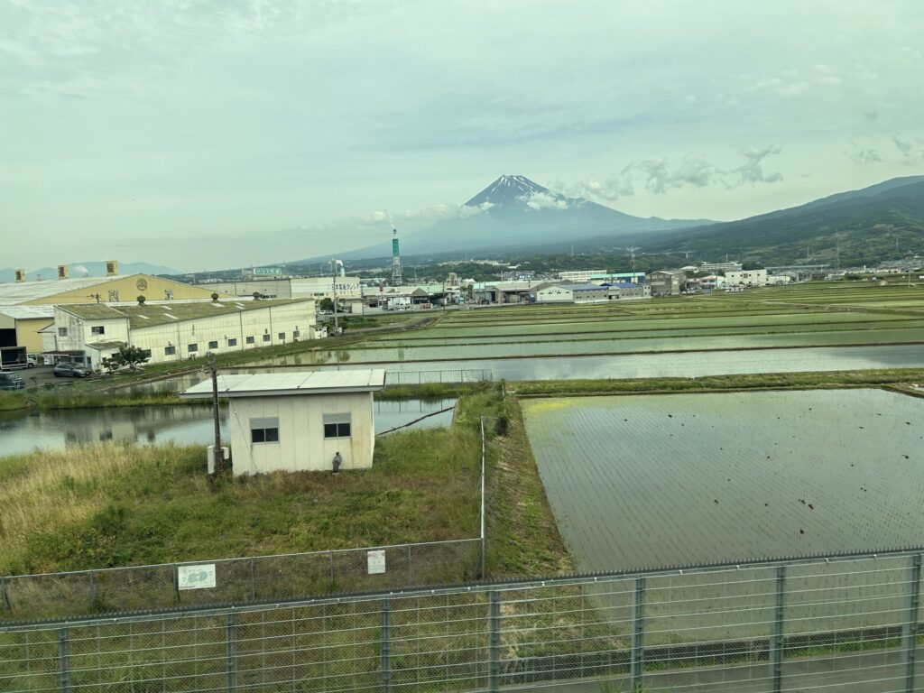 Snow-capped Mount Fuji above the clouds viewed from the Tokaido Shinkansen on a cloudy day in Japan.