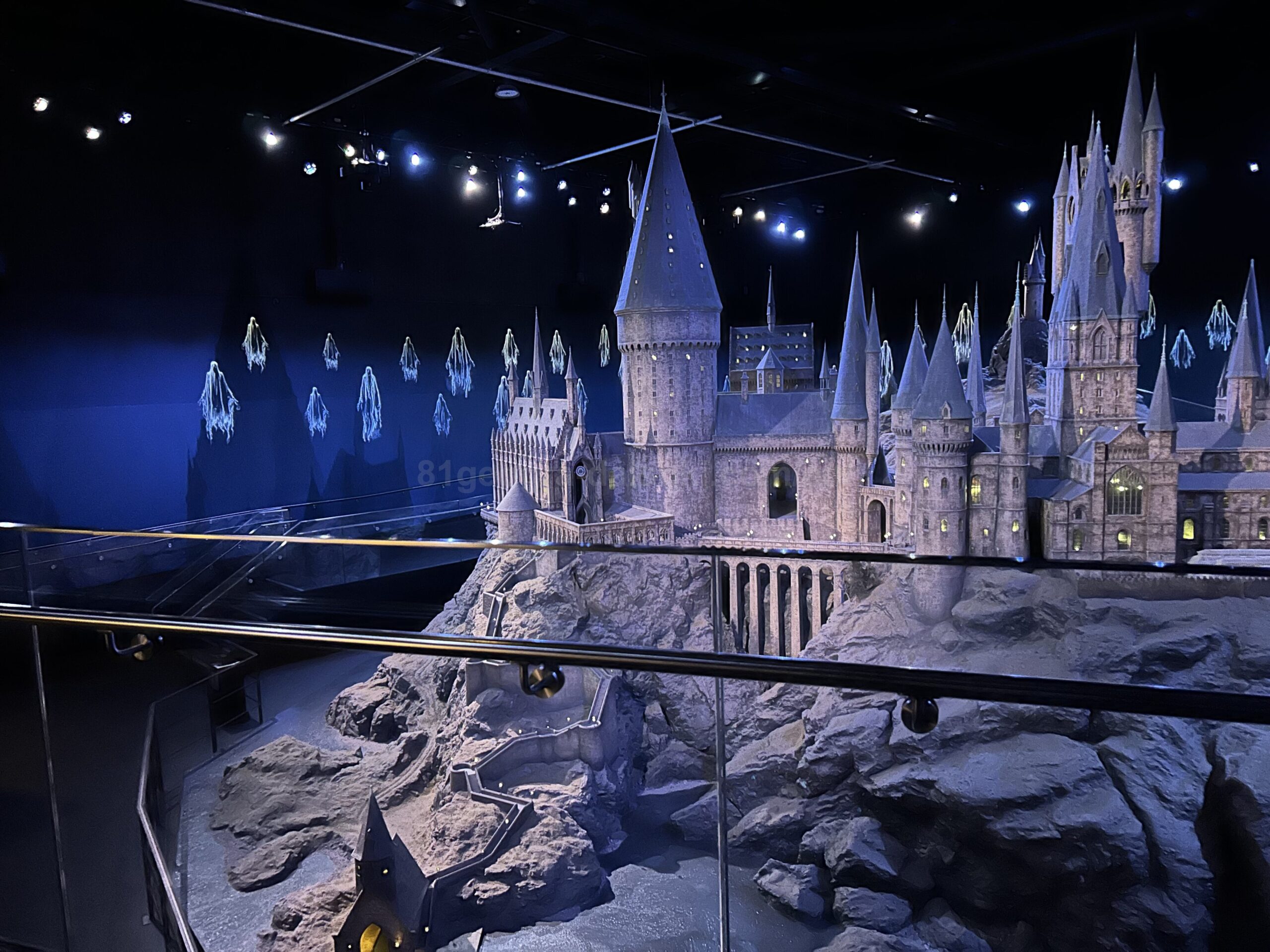 Detailed Hogwarts Castle model display at the Harry Potter Studio Tour in London with dramatic blue lighting and magical atmosphere.